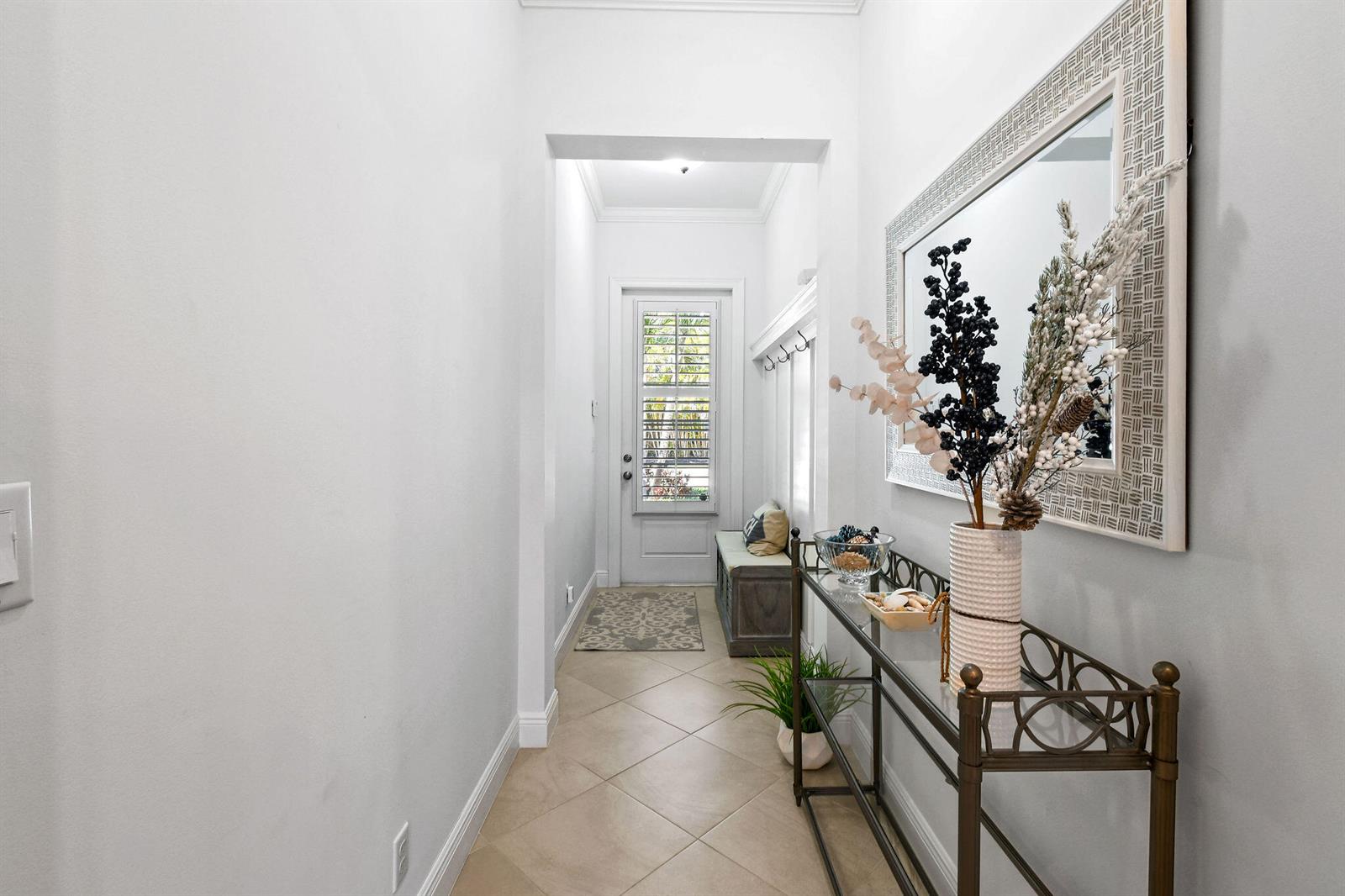 A bright entryway features a glass-topped console table, a wall mirror, and a tiled floor — 106 Ocean Breeze Drive, Juno Beach FL 33408, JUNO BEACH, FL