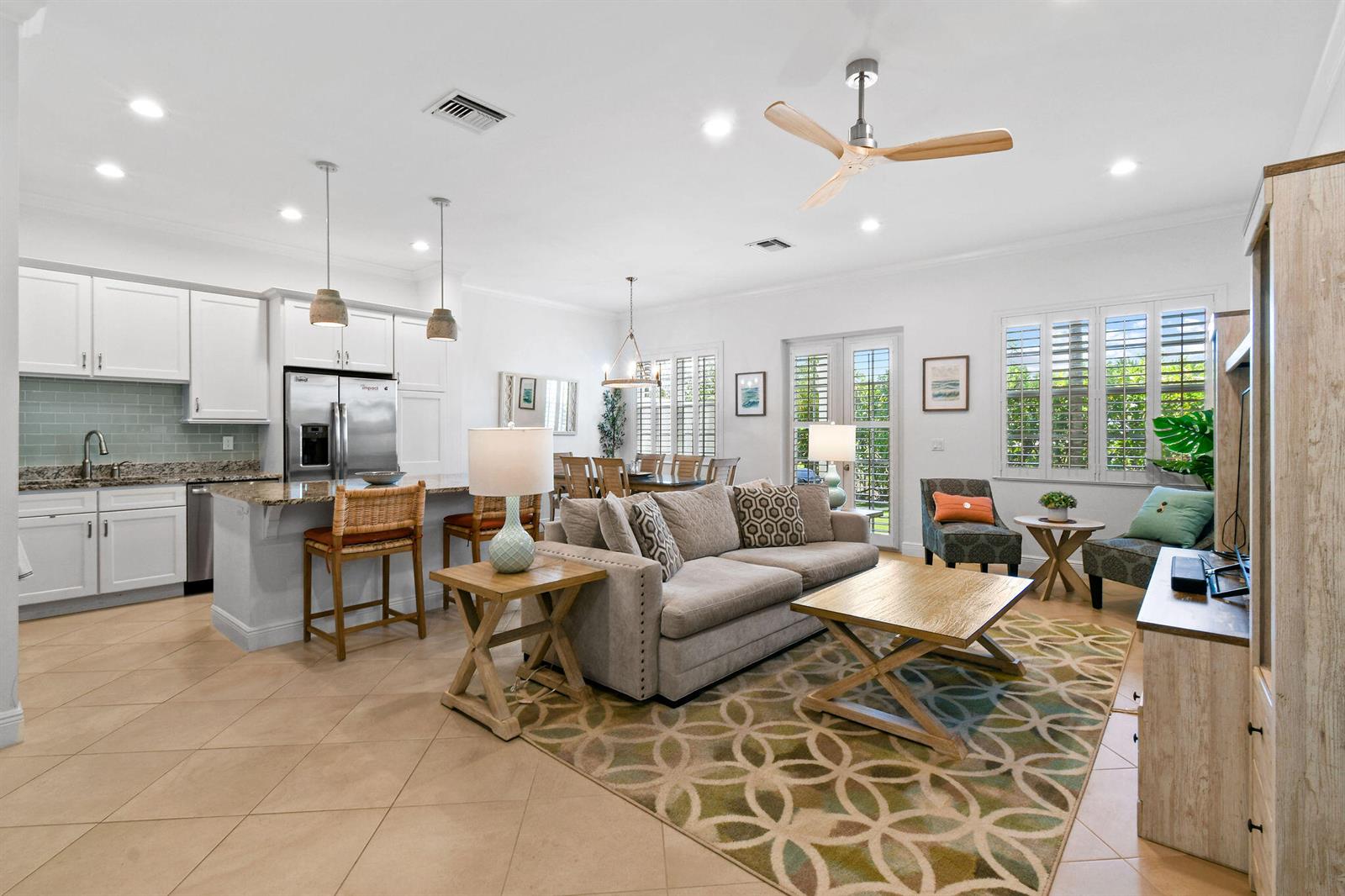 An open-concept living room and kitchen featuring white cabinetry, tile flooring, and a ceiling fan — 106 Ocean Breeze Drive, Juno Beach FL 33408, JUNO BEACH, FL