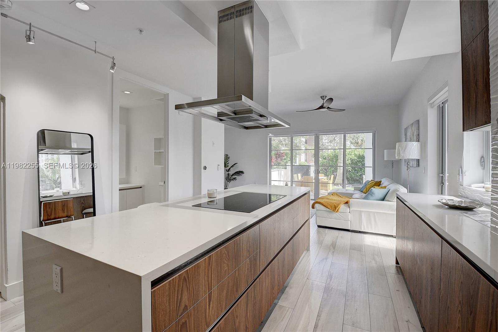 A modern kitchen features a large wooden island with a cooktop and white countertops — 155 E Boca Raton Rd, Boca Raton FL 33432, BOCA RATON, FL