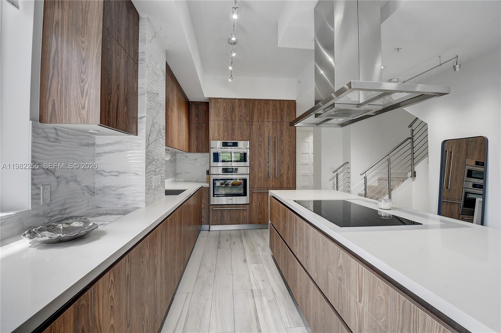 A modern kitchen features wood cabinetry, white countertops, a marble backsplash, and a central island — 155 E Boca Raton Rd, Boca Raton FL 33432, BOCA RATON, FL