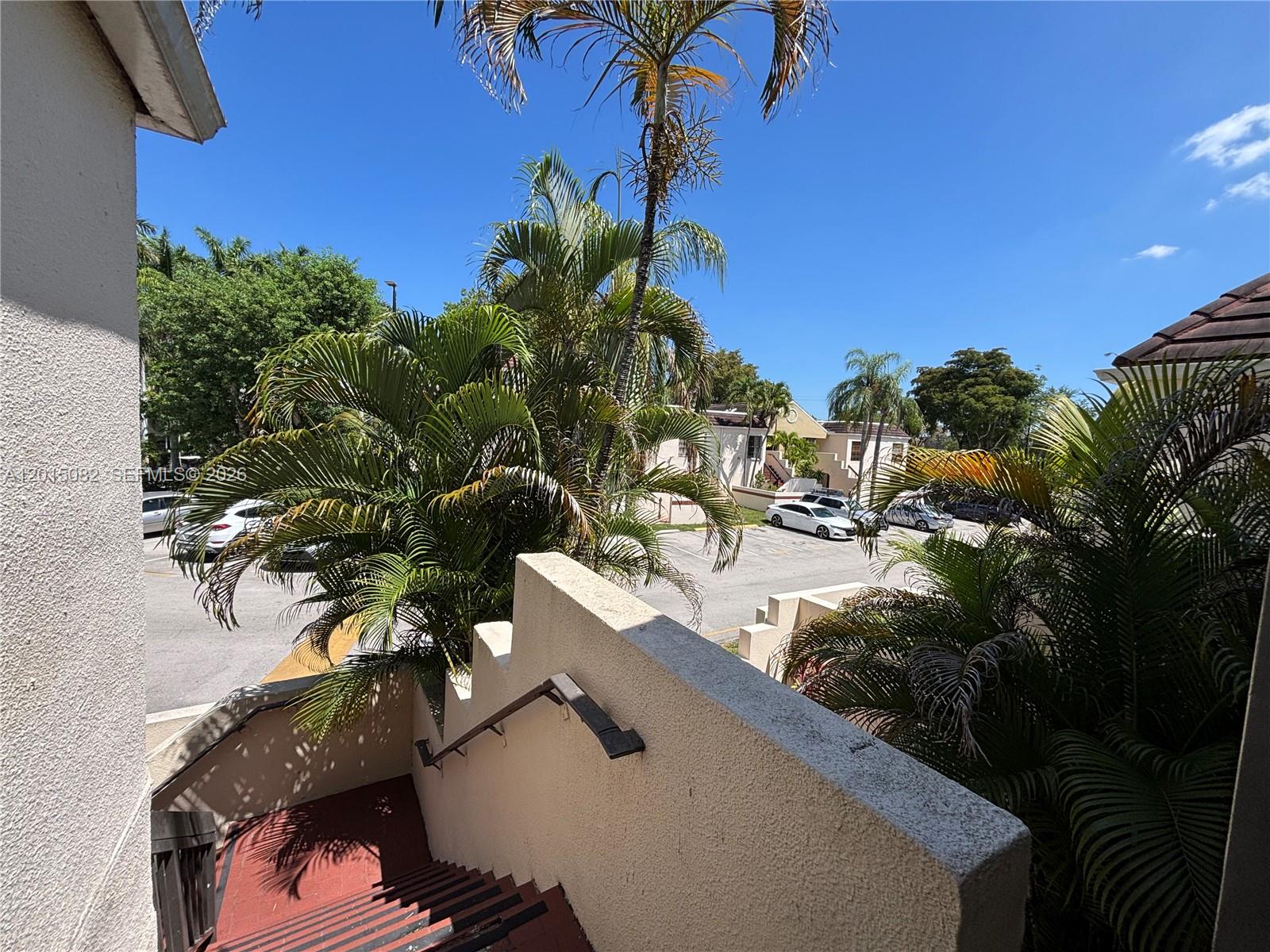 An outdoor staircase with a handrail leads down toward a parking lot with palm trees — 12922 SW 88th Ter # 206, Miami FL 33186, MIAMI, FL