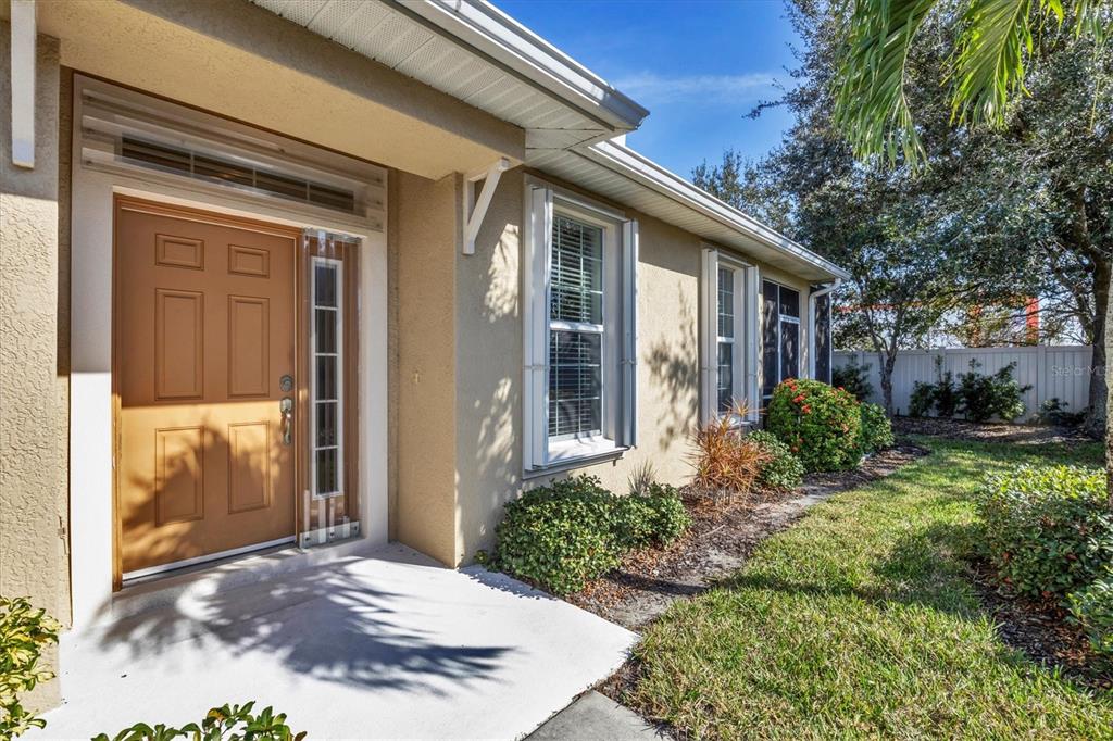 A tan house exterior features a brown front door, white trim, and a concrete porch — 2520 TERRACINA DRIVE, VENICE, FL
