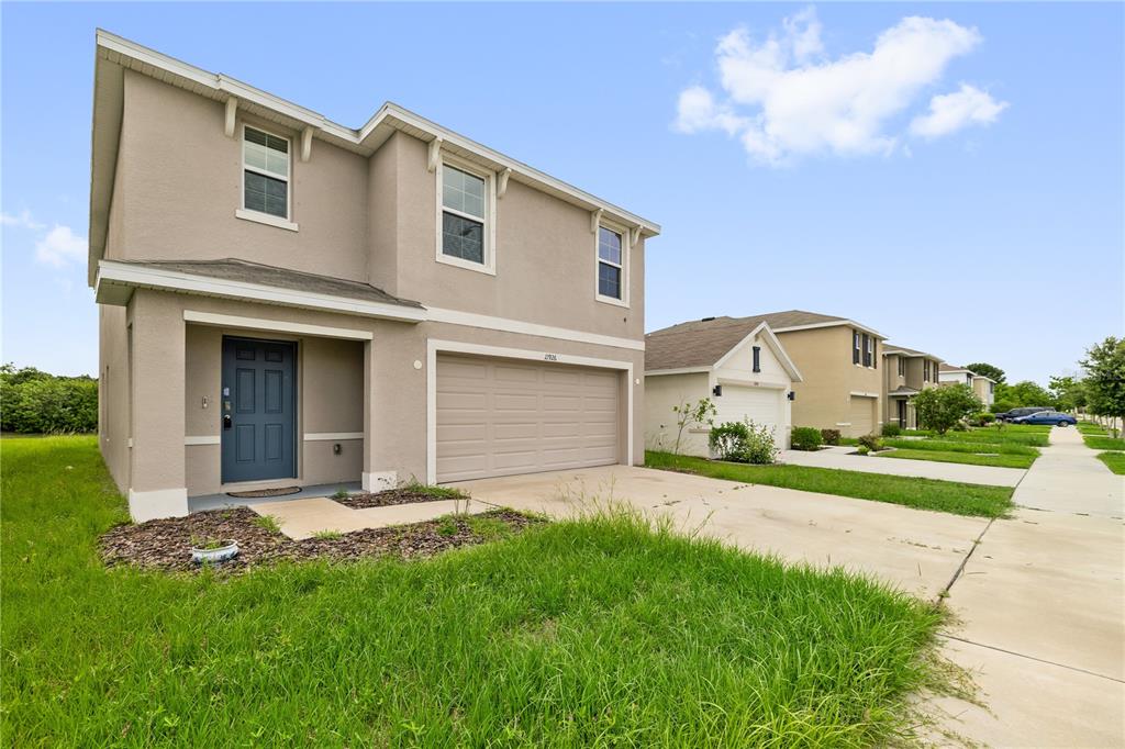 A two-story suburban house with a beige stucco exterior, a two-car garage, and a blue door — 11926 DOWNY BIRCH DRIVE, RIVERVIEW, FL