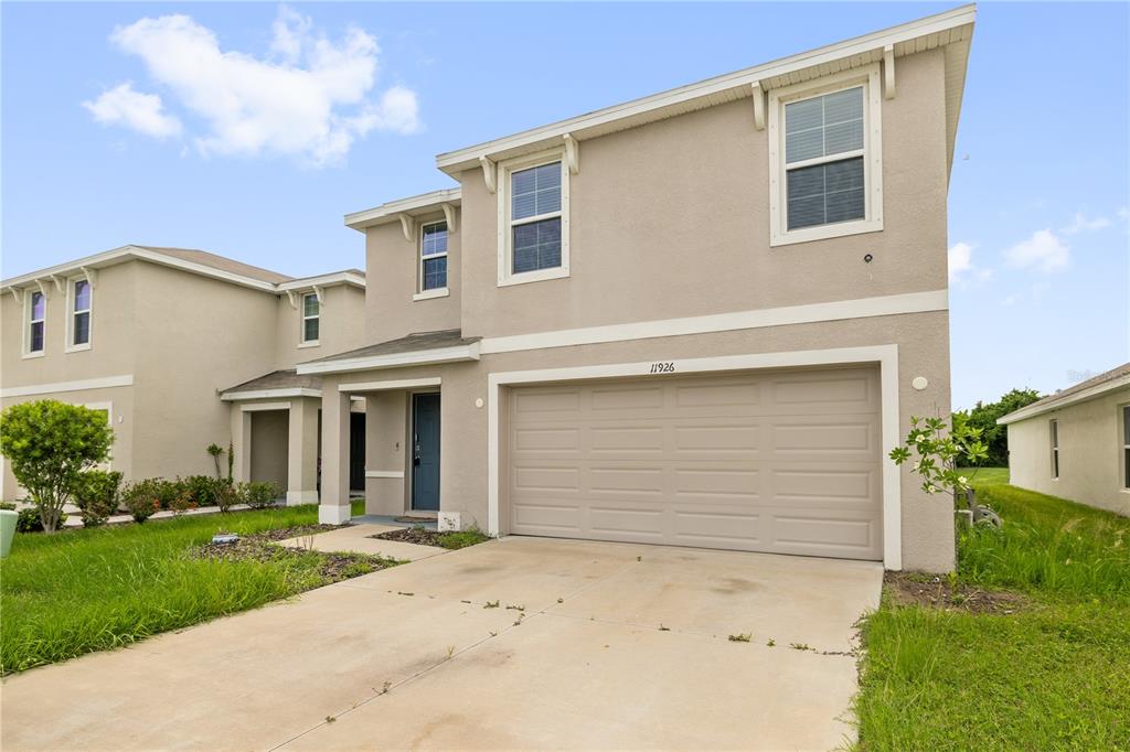 A two-story suburban house with a beige stucco exterior and a two-car garage — 11926 DOWNY BIRCH DRIVE, RIVERVIEW, FL