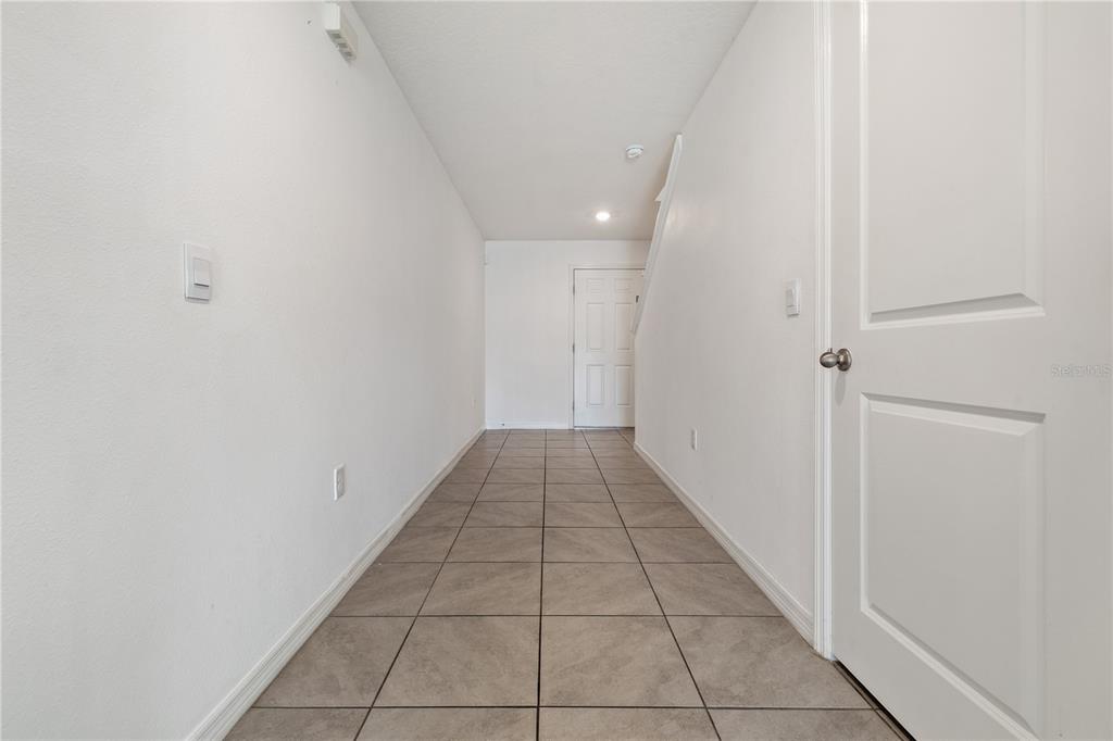 A tiled hallway leads to a white door with a staircase on the right — 11926 DOWNY BIRCH DRIVE, RIVERVIEW, FL
