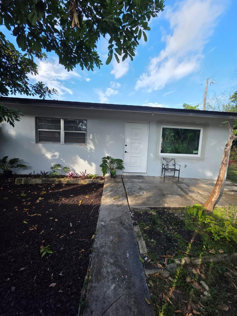 A single-story house exterior with a white door, a large window, and a concrete walkway — 3386 Rudolph Road, FL 33461, FL