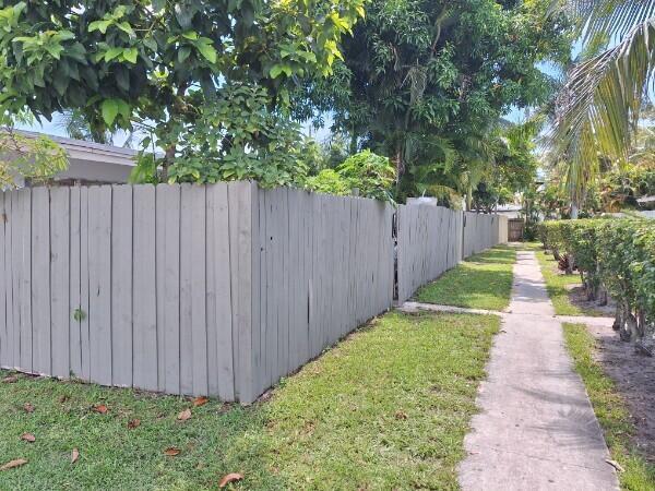 A gray wooden privacy fence runs along a concrete sidewalk next to a grassy yard — 3386 Rudolph Road, FL 33461, FL