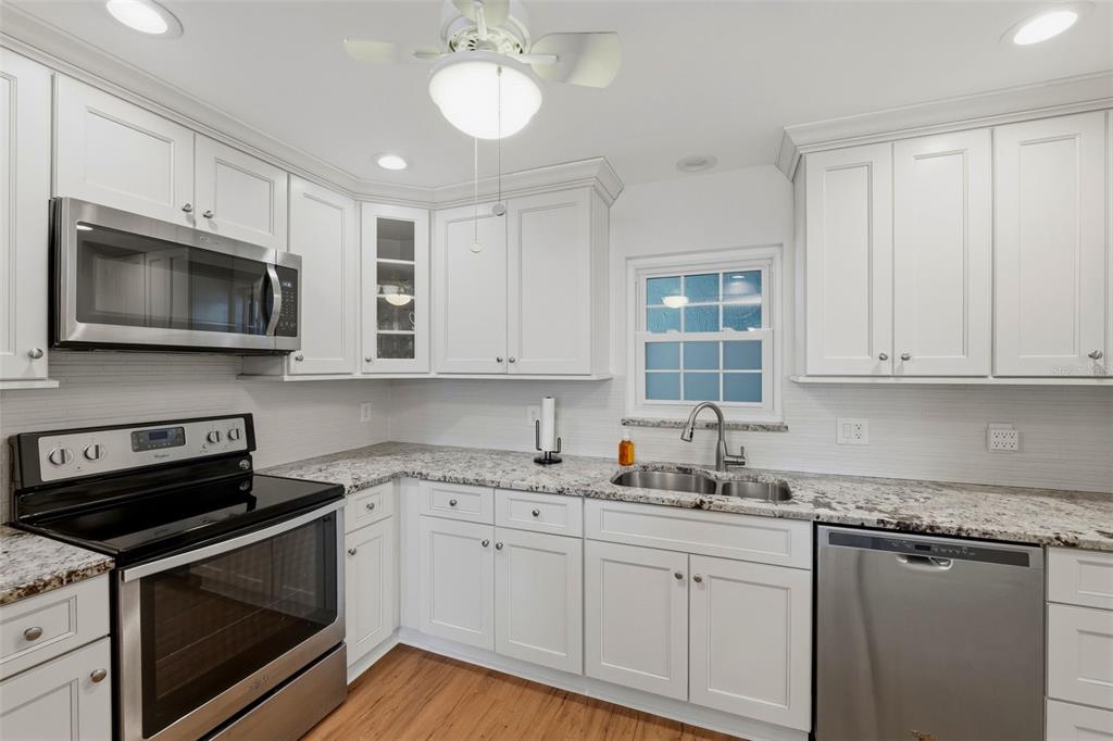 A kitchen with white cabinets, stainless steel appliances, and granite countertops — 1706 BELLEAIR FOREST DRIVE UNIT 234, BELLEAIR, FL