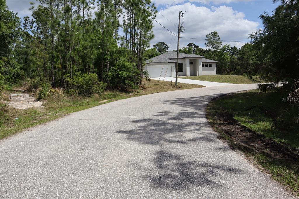A newly constructed single-story house sits at the end of a paved residential road — LACOCO STREET, NORTH PORT, FL