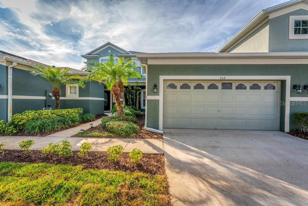 A two-story house with a green exterior, a two-car garage, and a landscaped front walkway — 868 STONECHASE LANE, LAKE MARY, FL