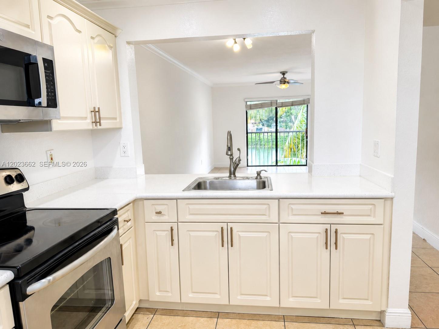 A kitchen features cream cabinets, stainless steel appliances, white countertops, and a view of water — 7668 SW 152nd Ave # 206, Miami FL 33193, MIAMI, FL