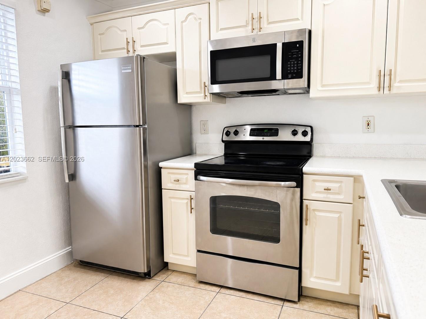 A kitchen features stainless steel appliances, off-white cabinets, and light-colored tile flooring — 7668 SW 152nd Ave # 206, Miami FL 33193, MIAMI, FL