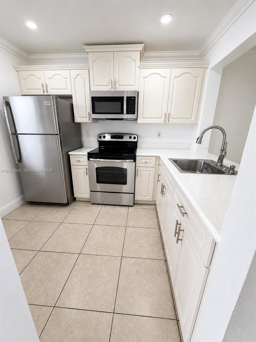 A kitchen features white cabinets, stainless steel appliances, and light-colored tile flooring — 7668 SW 152nd Ave # 206, Miami FL 33193, MIAMI, FL