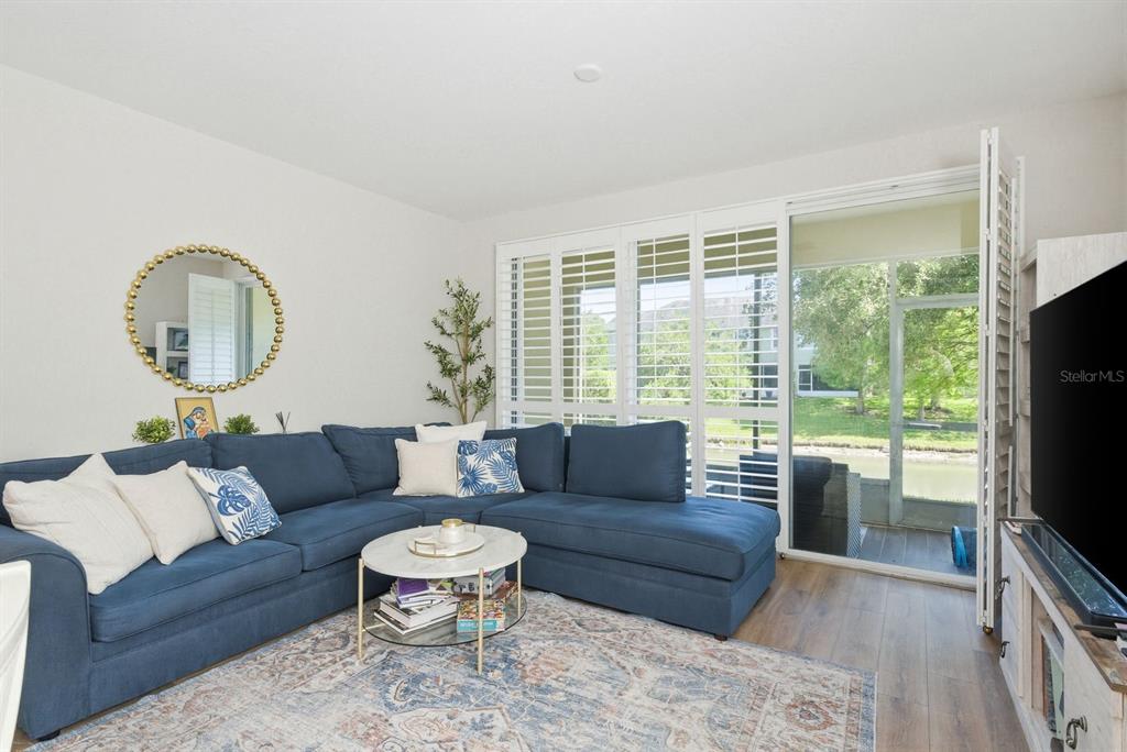 A living room features a blue sectional sofa, a round coffee table, and sliding glass doors — 336 HARBOR RIDGE DRIVE, PALM HARBOR, FL