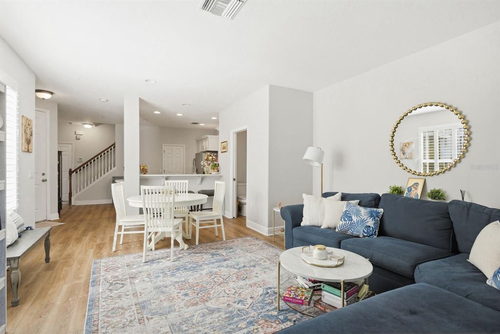 An open-concept living and dining area features a blue sectional sofa, white furniture, and flooring — 336 HARBOR RIDGE DRIVE, PALM HARBOR, FL