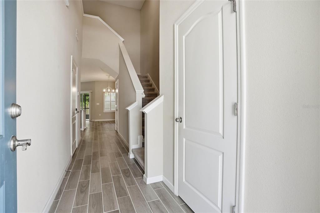 A foyer with wood-look tile flooring leads to a staircase and a hallway beyond — 1680 POTTSBURG POINT DRIVE, JACKSONVILLE, FL