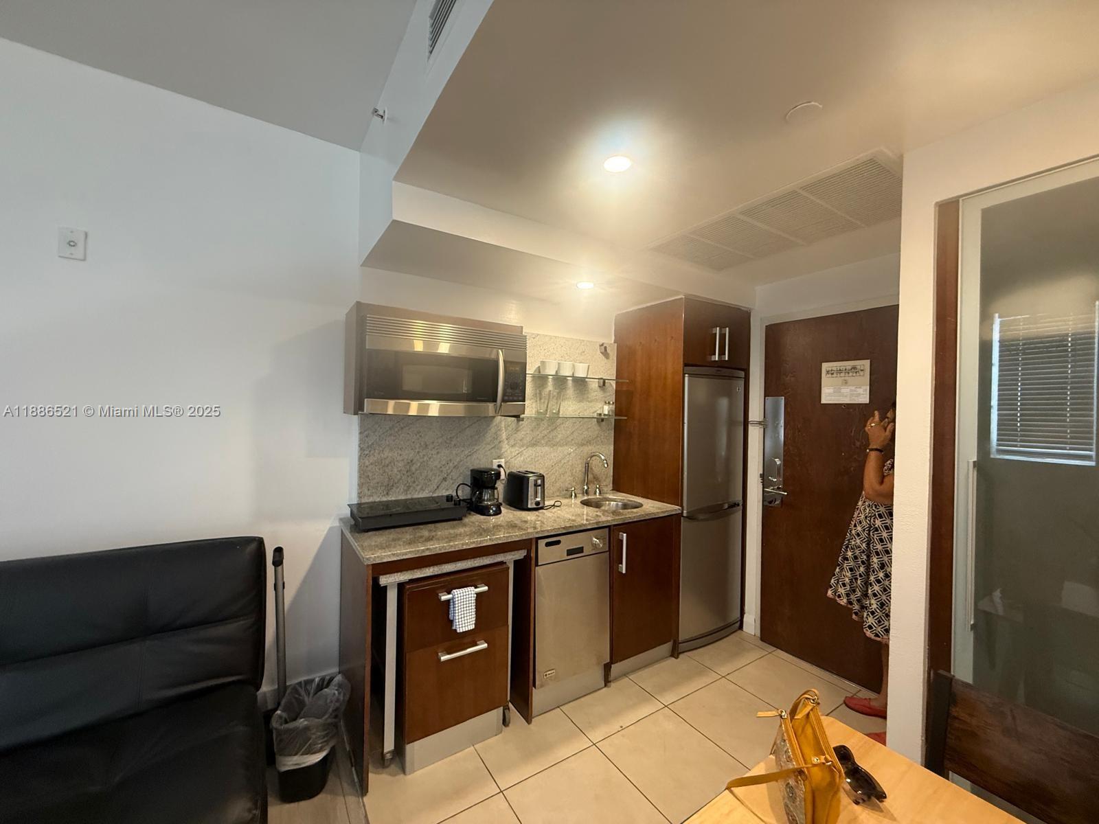 A small kitchenette features stainless steel appliances, dark wood cabinetry, and granite countertops — 1036 Ocean Dr # B309, Miami Beach FL 33139, MIAMI BEACH, FL