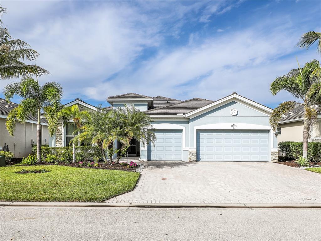 A light blue house with a three-car garage and palm trees in the front yard — 16391 BONITA LANDING CIRCLE, BONITA SPRINGS, FL