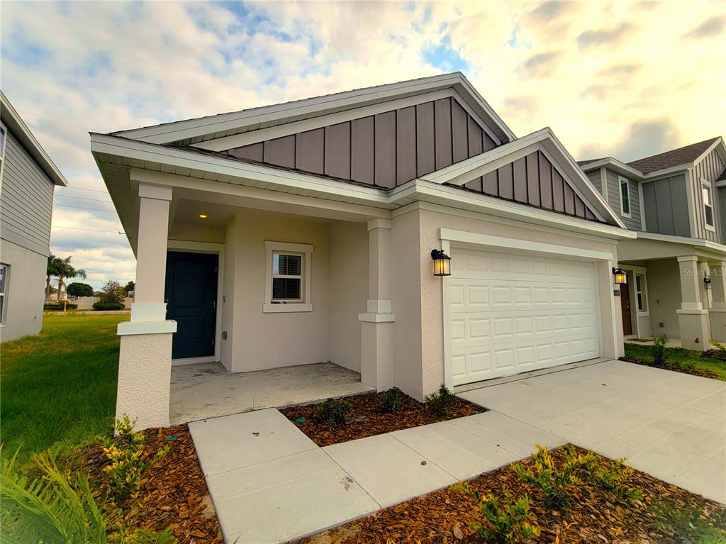 A single-story house exterior features a covered entryway, a white garage door, and metal siding — 1469 DEEPWATER CIRCLE, EAGLE LAKE, FL
