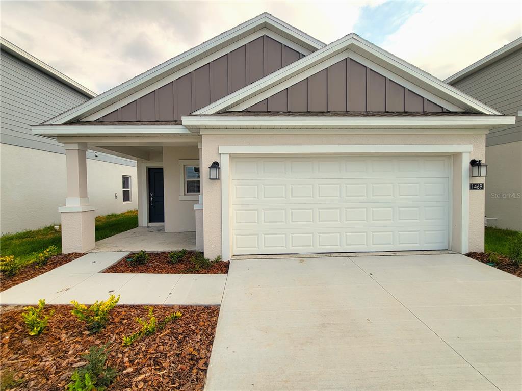 A single-story house features a beige stucco exterior, a two-car garage, and a covered entryway — 1469 DEEPWATER CIRCLE, EAGLE LAKE, FL