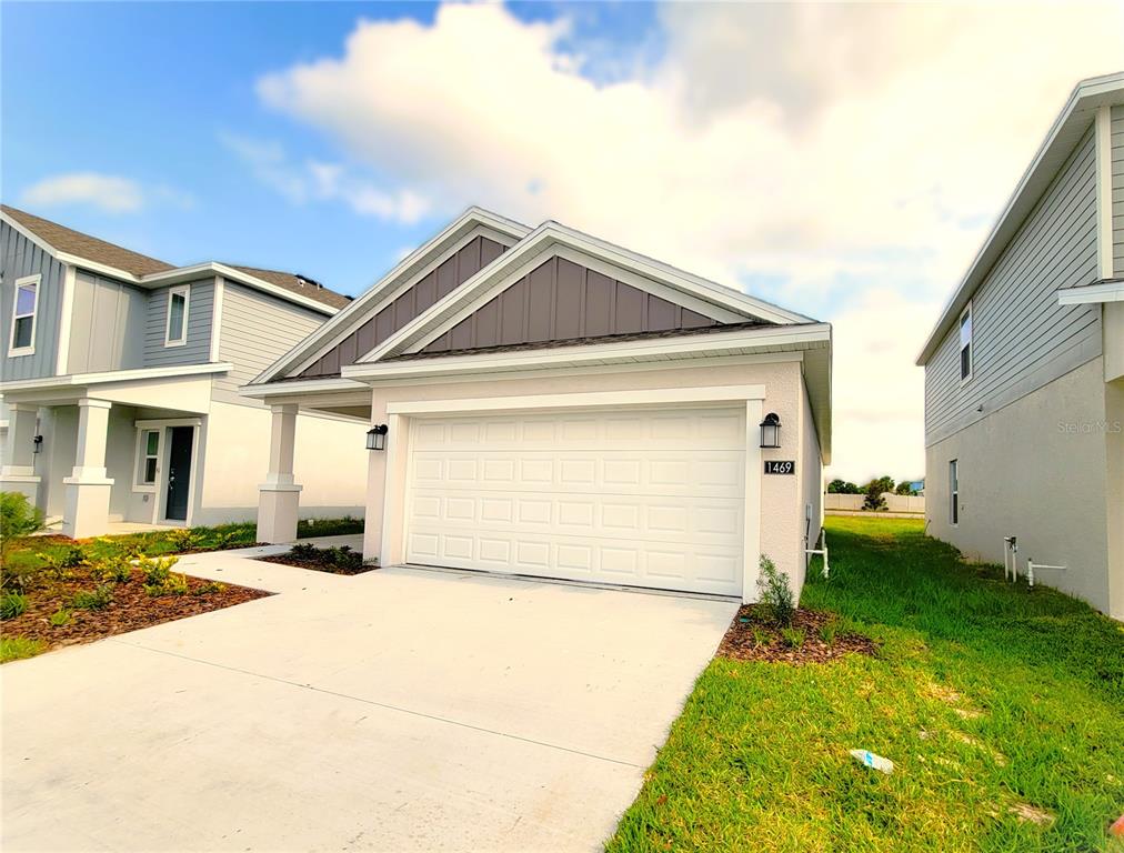 A single-story house with a white garage door, light-colored siding, and a concrete driveway — 1469 DEEPWATER CIRCLE, EAGLE LAKE, FL