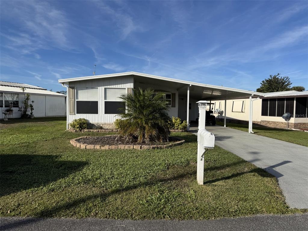 A single-story manufactured home features a carport, a palm tree, and a small front lawn — 9138 LAKE POINT BOULEVARD, LAKE WALES, FL