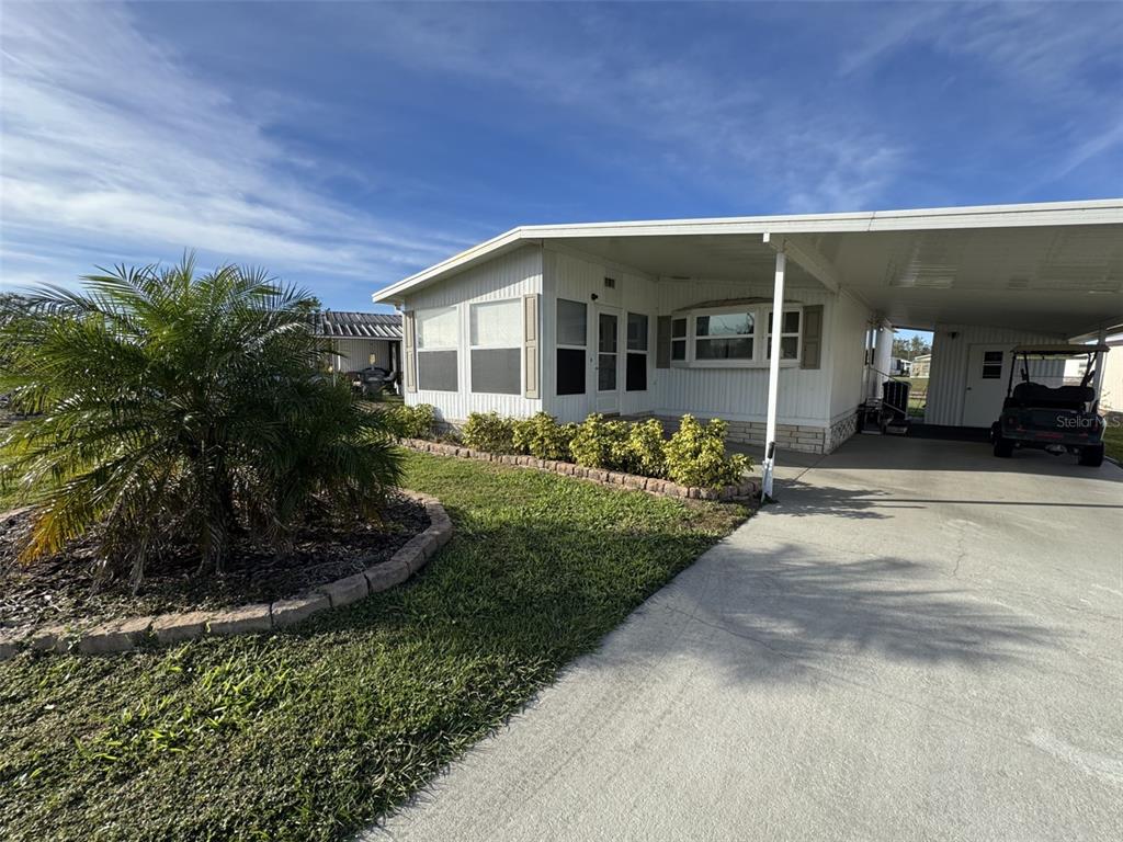 A white mobile home with a carport, a palm tree, and a concrete driveway — 9138 LAKE POINT BOULEVARD, LAKE WALES, FL