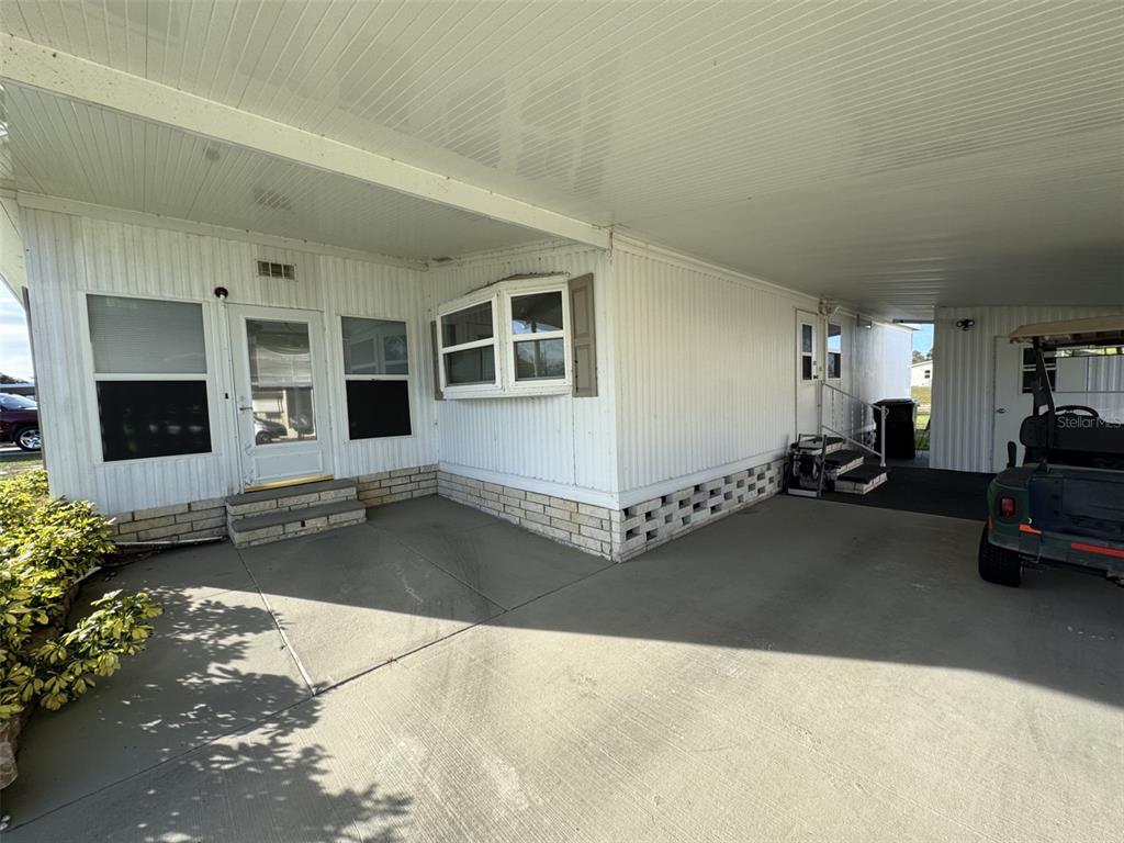 A white mobile home exterior features a covered carport, concrete patio, and a bay window — 9138 LAKE POINT BOULEVARD, LAKE WALES, FL