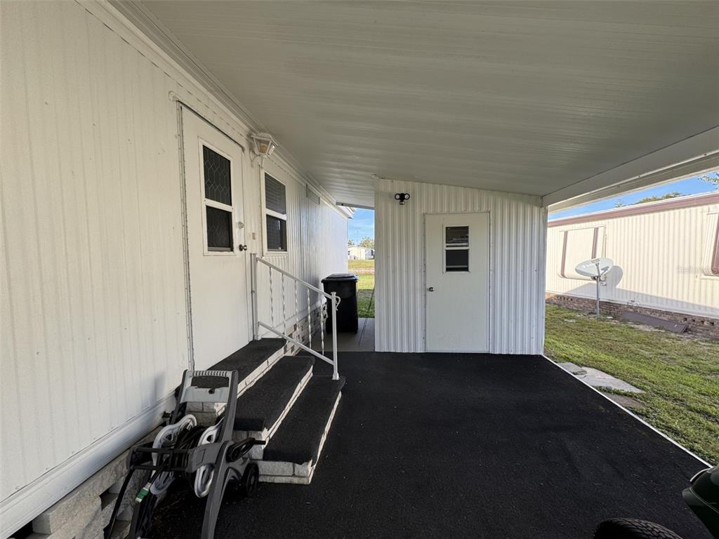 A white mobile home exterior features a covered carport, stairs, and a small storage shed — 9138 LAKE POINT BOULEVARD, LAKE WALES, FL