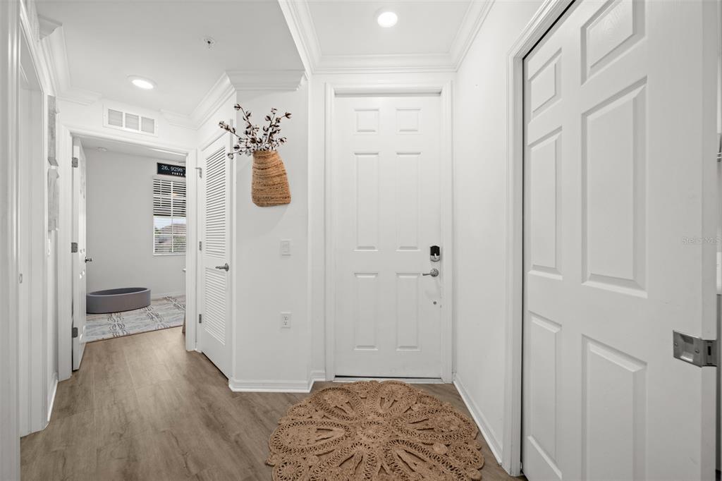 A white entryway features a front door, a round jute rug, and a hallway entrance — 43030 GREENWAY BOULEVARD UNIT 428, PUNTA GORDA, FL
