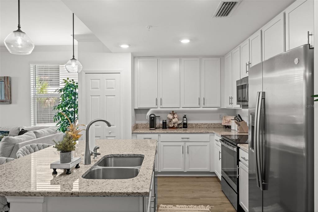 A kitchen features white cabinets, granite countertops, a stainless steel refrigerator, and a center island — 43030 GREENWAY BOULEVARD UNIT 428, PUNTA GORDA, FL