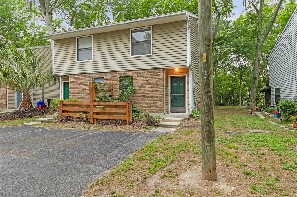 A two-story townhouse with tan siding, a brick lower level, and a wooden privacy fence — 4526 SW 44TH LANE UNIT 4526, GAINESVILLE, FL