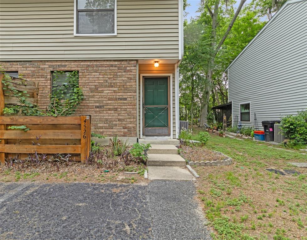 A two-story townhouse with a brick and siding exterior, a green door, and a walkway — 4526 SW 44TH LANE UNIT 4526, GAINESVILLE, FL
