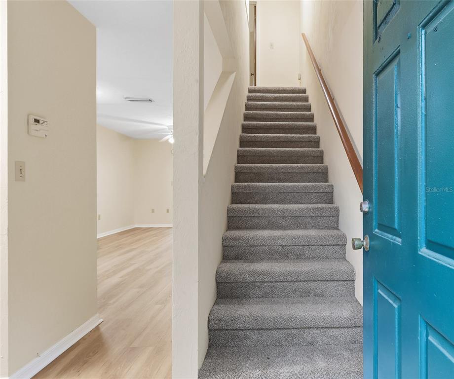 A carpeted staircase leads upward next to an entryway opening into a room with flooring — 4526 SW 44TH LANE UNIT 4526, GAINESVILLE, FL