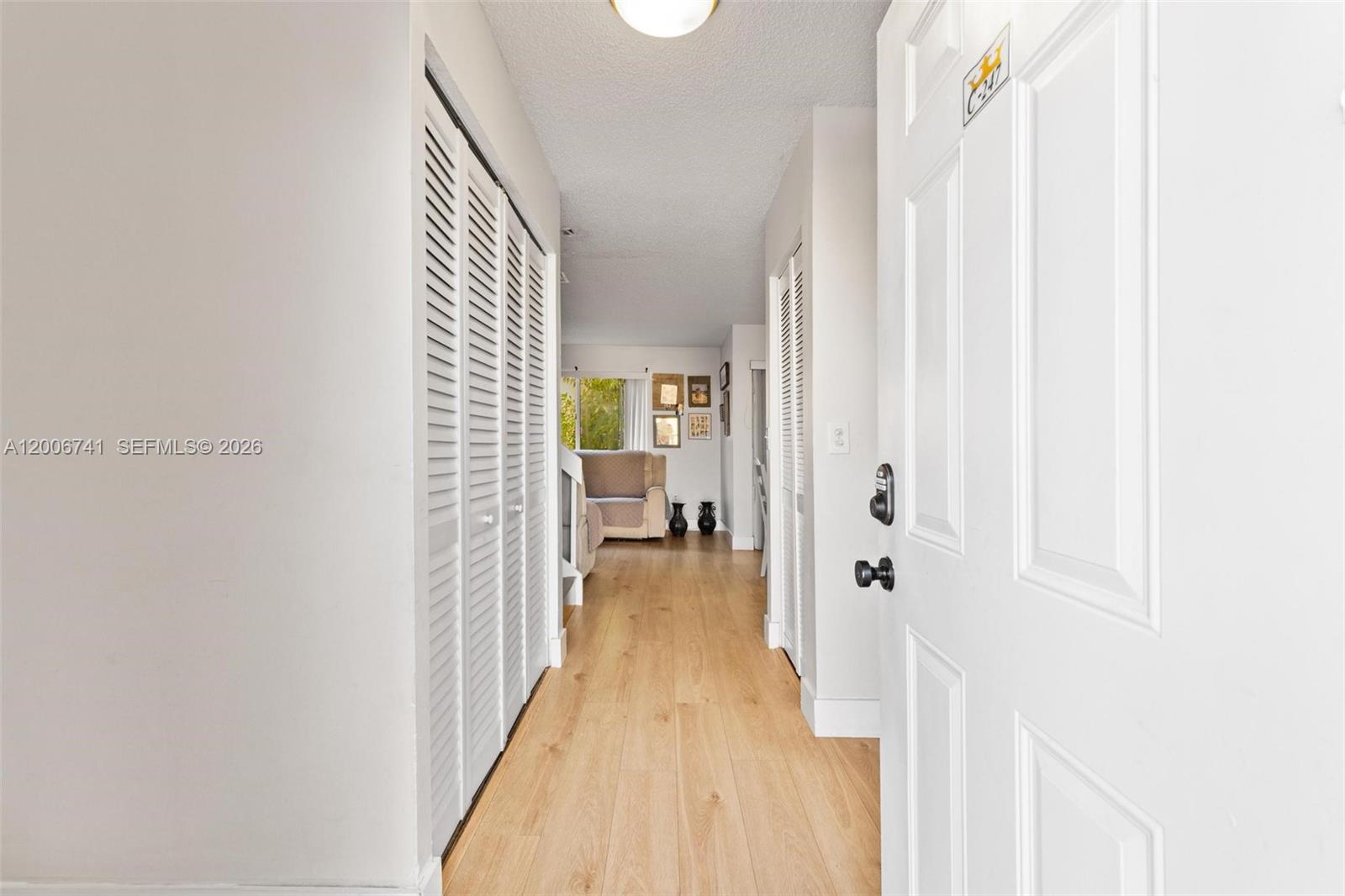 A hallway with light wood flooring leads from an open door toward a living area — 6235 Kendale Lakes Cir # 247, Miami FL 33183, MIAMI, FL