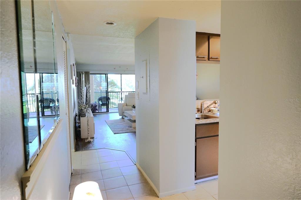 A view from a tiled entryway looking toward a living room with a balcony — 1999 KINGS HIGHWAY UNIT 16B, PUNTA GORDA, FL