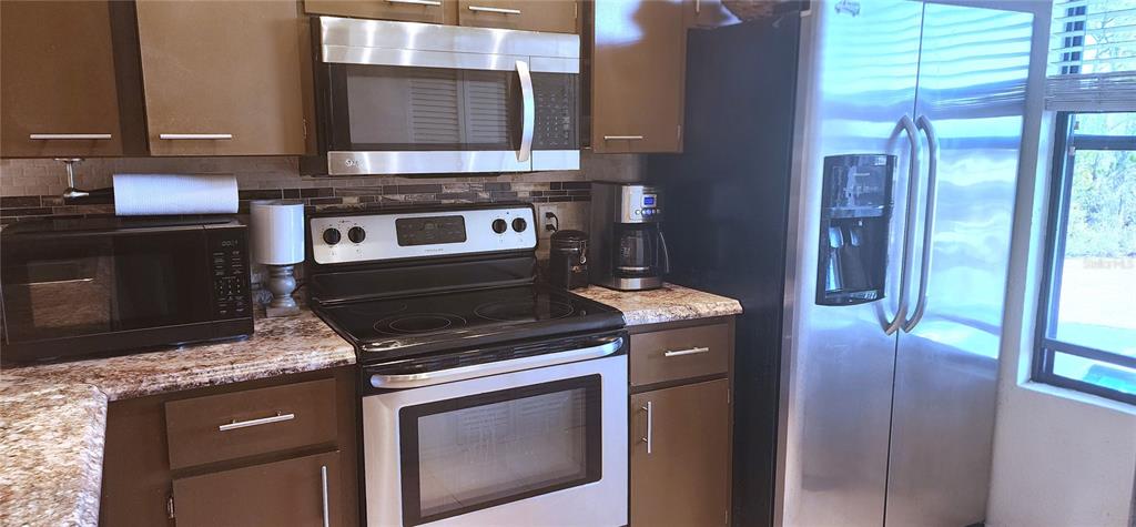 A kitchen features brown cabinets, stainless steel appliances, and granite countertops — 1999 KINGS HIGHWAY UNIT 16B, PUNTA GORDA, FL