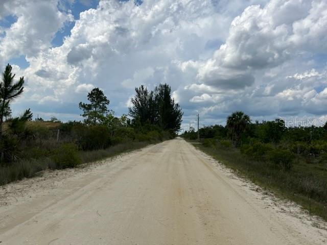 A dirt road stretches through a rural landscape under a cloudy sky — 50670 BERMONT ROAD, PUNTA GORDA, FL