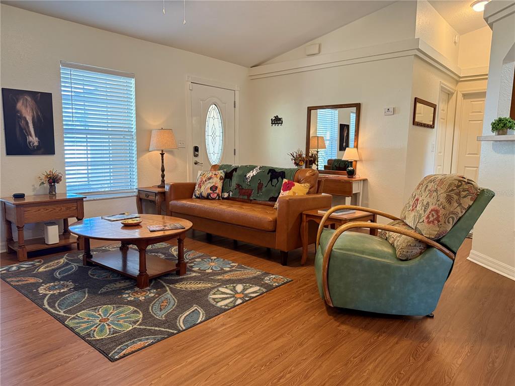 A living room features a leather sofa, a green armchair, and a patterned area rug — 6470 NW 56TH TERRACE, OCALA, FL