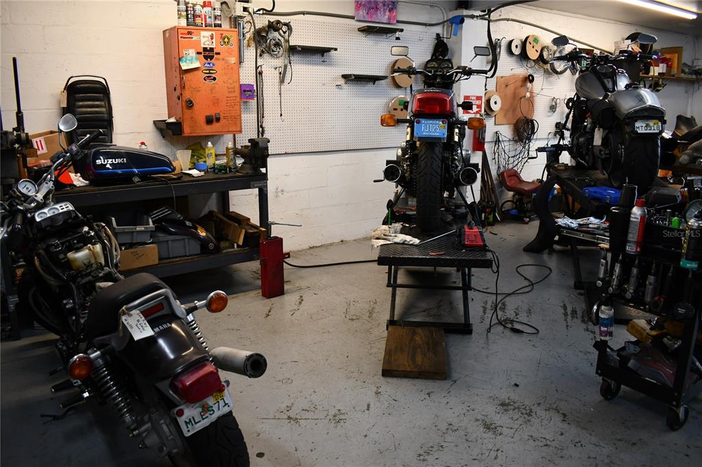 A motorcycle repair shop features three motorcycles, a workbench, and various tools on pegboard walls — 2702 E 7TH AVENUE, TAMPA, FL