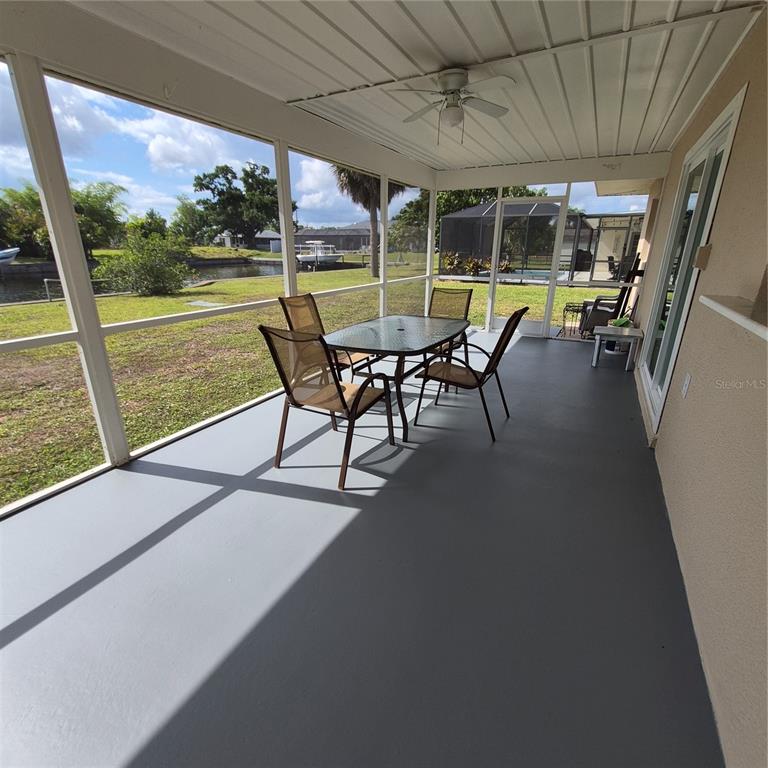 A screened-in patio features a dining set, gray flooring, and a view of a canal — 5290 NEVILLE TERRACE, PORT CHARLOTTE, FL