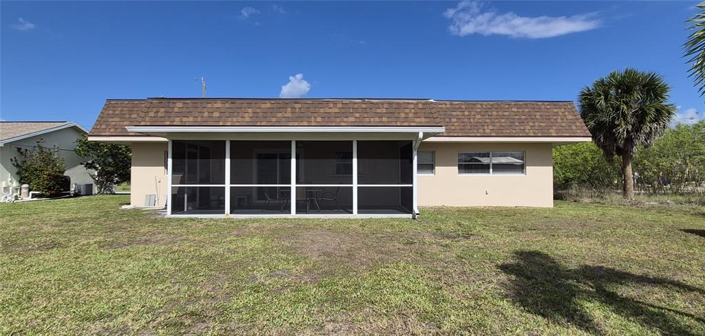 The exterior of a single-story house features a screened-in patio and a brown shingled roof — 5290 NEVILLE TERRACE, PORT CHARLOTTE, FL