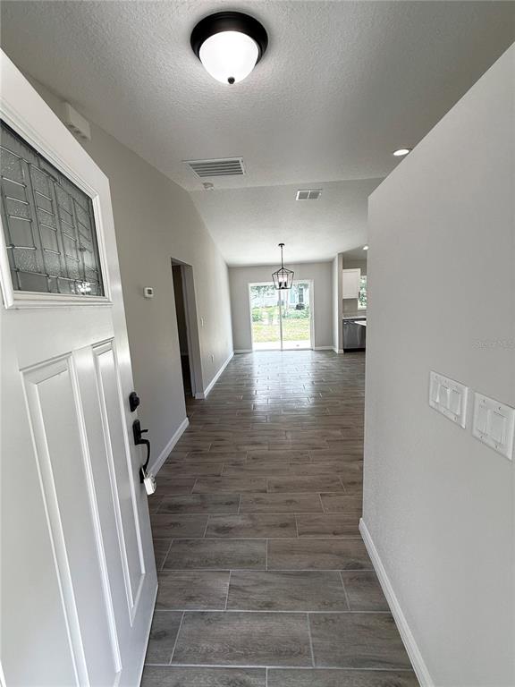 An entryway opens into a living area with wood-look tile flooring and a sliding door — 5687 NW 57TH STREET, OCALA, FL