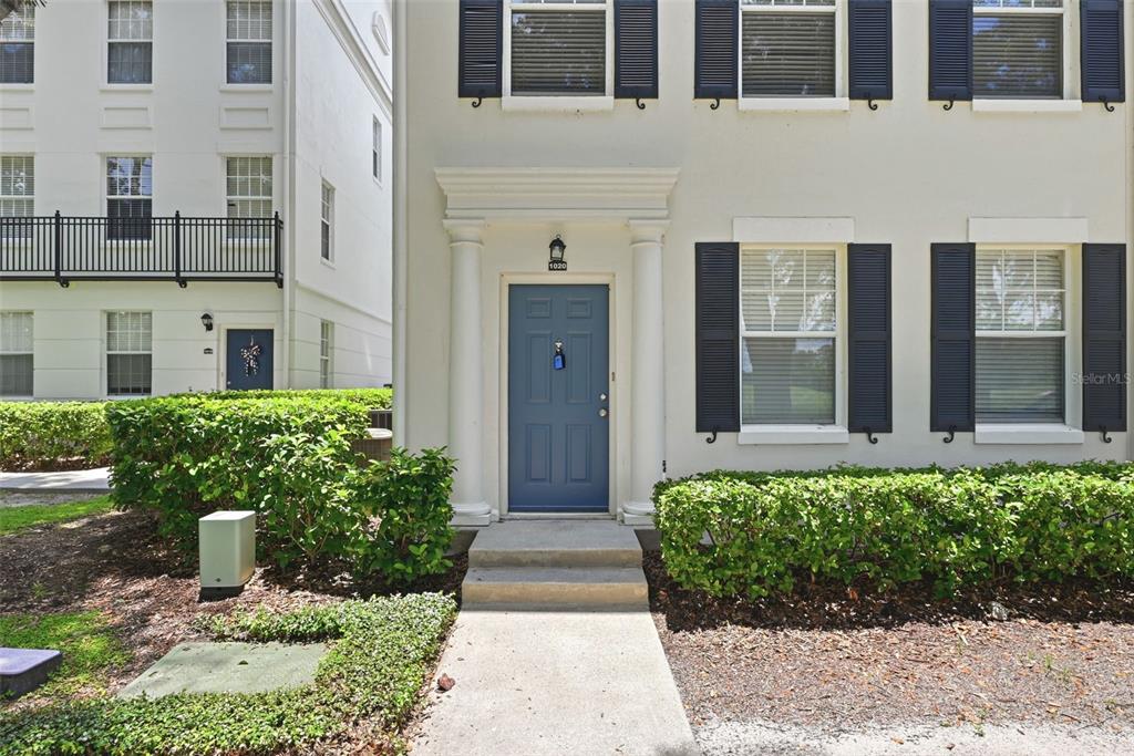 The exterior of a multi-story townhouse features a blue front door with white columns — 1020 WATERSIDE DRIVE UNIT 1020, CELEBRATION, FL