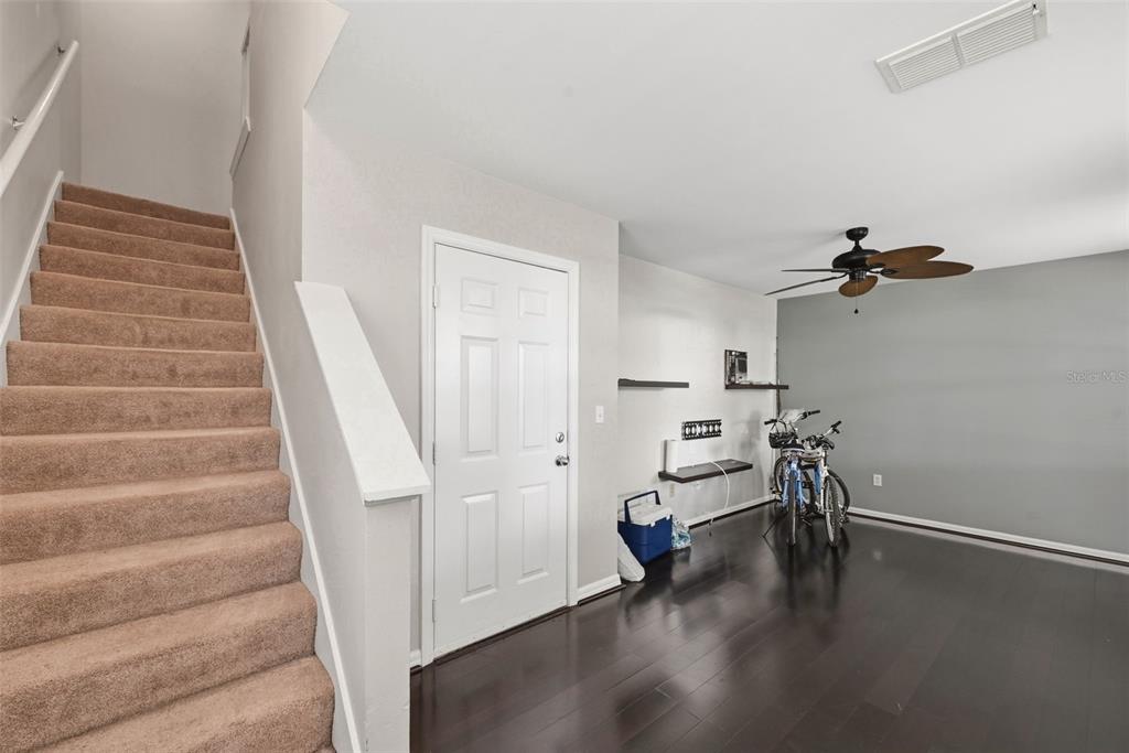 A room with dark wood floors, carpeted stairs, a white door, and two bicycles — 1020 WATERSIDE DRIVE UNIT 1020, CELEBRATION, FL