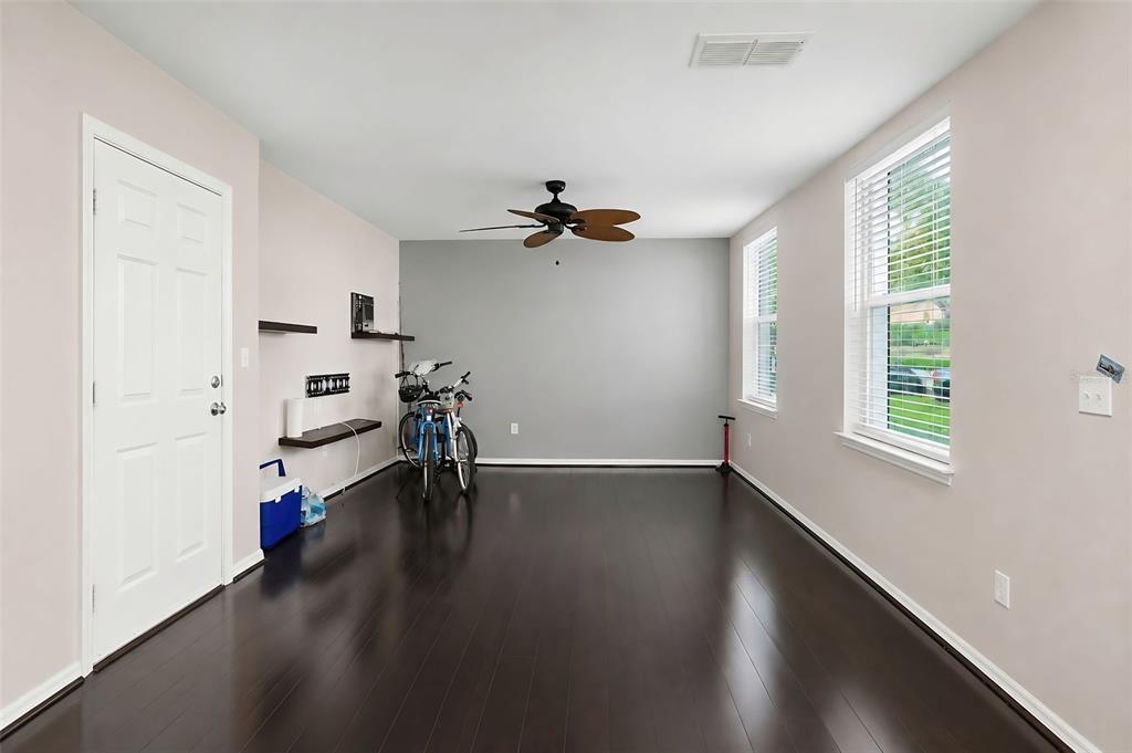 A room with dark wood floors, a ceiling fan, two windows, and two bicycles — 1020 WATERSIDE DRIVE UNIT 1020, CELEBRATION, FL