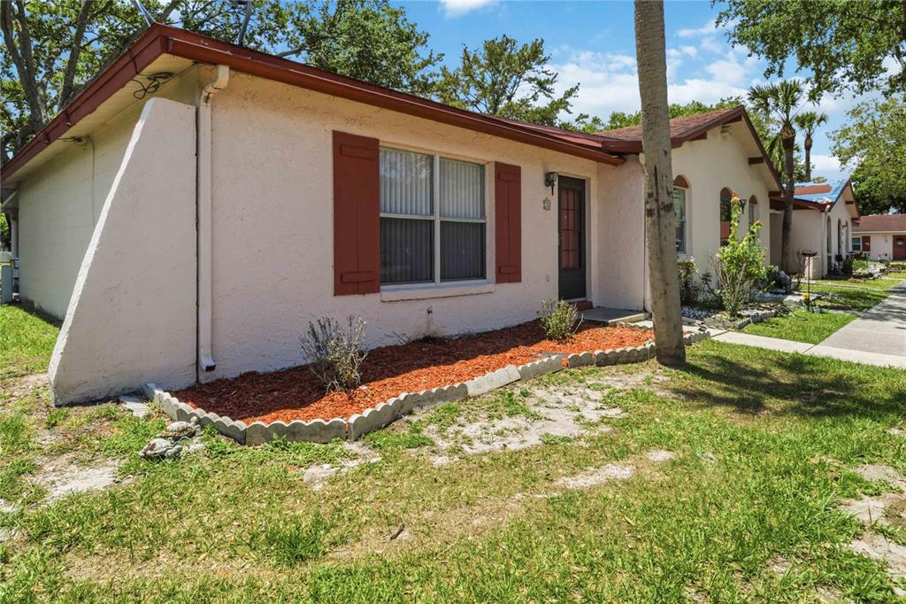 A single-story house with beige stucco walls, red shutters, and a small front garden bed — 74 S MARBRISA WAY, KISSIMMEE, FL