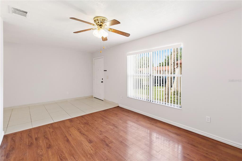 A room with wood-look flooring, a tiled entryway, a ceiling fan, and vertical window blinds — 74 S MARBRISA WAY, KISSIMMEE, FL