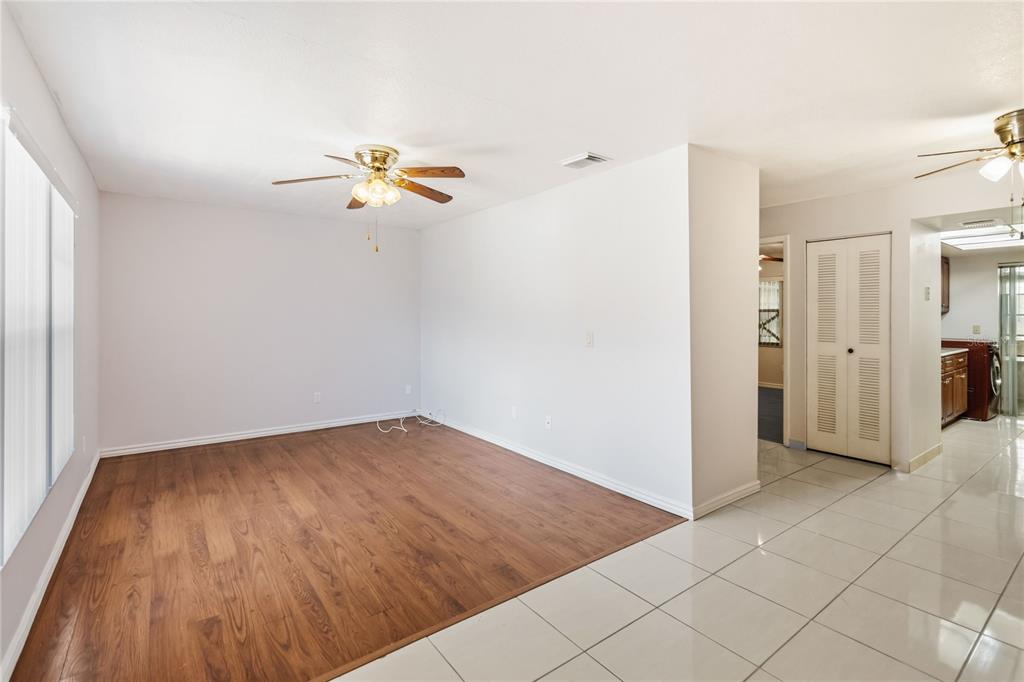 A room with wood-look flooring transitions to white tile, featuring a ceiling fan and closet — 74 S MARBRISA WAY, KISSIMMEE, FL