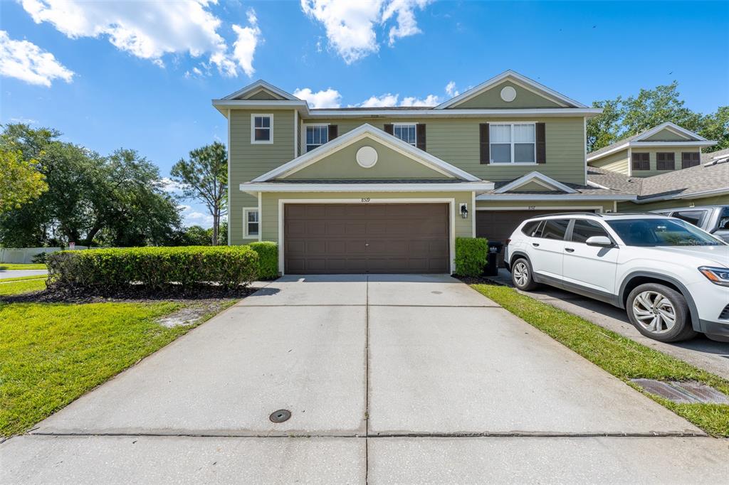 A two-story house with green siding, a brown garage door, and a concrete driveway — 8519 BROKEN WILLOW COURT, TAMPA, FL